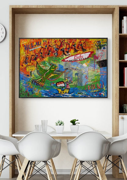 Das Gemälde „Von Löffeln, Helau und der Sehnsucht nach Köln“ von Jasmin Meirose hängt in einem modernen, hell eingerichteten Raum über einem Esstisch mit weißen Stühlen. Das farbenfrohe Werk zeigt humorvolle karnevalistische Motive, eine grüne Dinofigur und Anspielungen auf Kölns Lebensfreude.